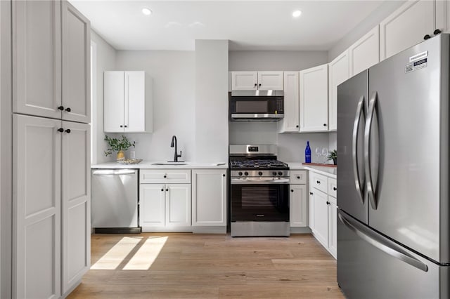 7314 Monticello St, Homewood-Brushton, PA 15208 - kitchen with light wood-style floors, light countertops, white cabinets, a sink, and appliances with stainless steel finishes