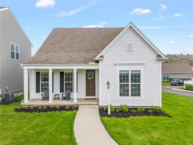 view of front of home with central air condition unit, a porch, roof with shingles, and a front yard