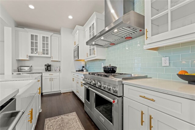 kitchen with appliances with stainless steel finishes, white cabinets, dark wood-style floors, and wall chimney exhaust hood