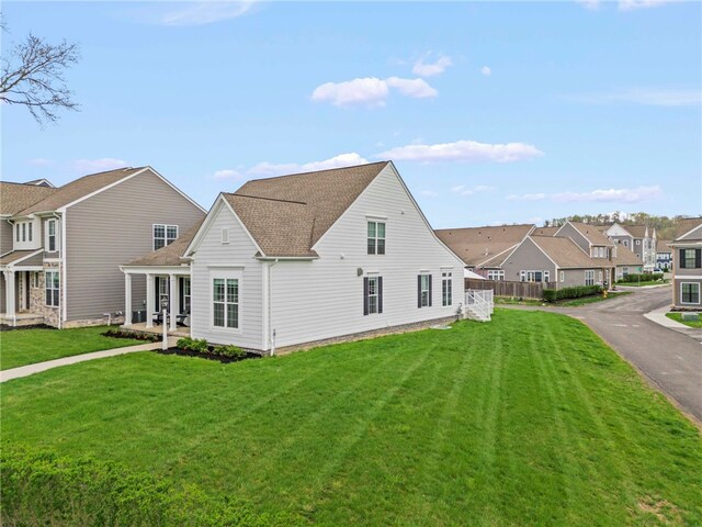 view of home's exterior featuring a residential view, a shingled roof, and a lawn