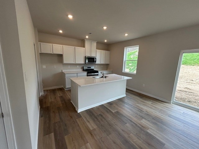 kitchen with light countertops, appliances with stainless steel finishes, plenty of natural light, and white cabinets