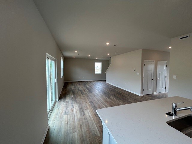 unfurnished living room with baseboards, visible vents, a sink, and wood finished floors