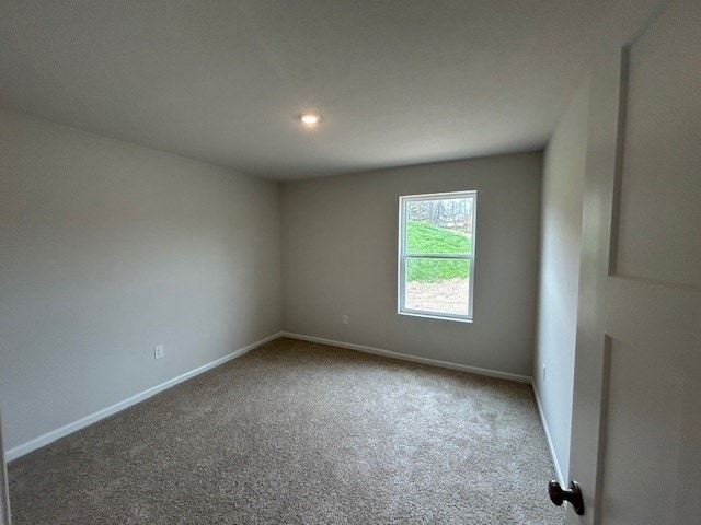 carpeted empty room featuring baseboards