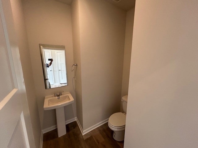 bathroom featuring toilet, baseboards, a sink, and wood finished floors