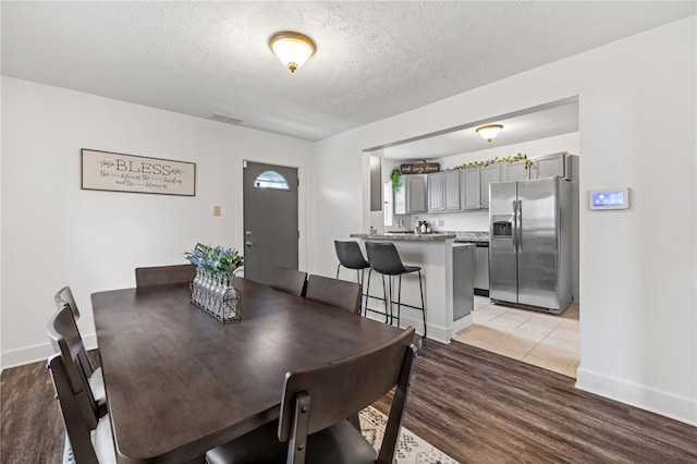 1629 Davidson St, Aliquippa, PA 15001 - dining space with baseboards, light wood finished floors, a textured ceiling, and visible vents