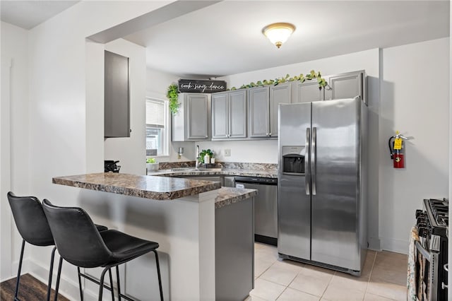 1629 Davidson St, Aliquippa, PA 15001 - kitchen with gray cabinets, a breakfast bar area, a peninsula, stainless steel appliances, and light tile patterned flooring