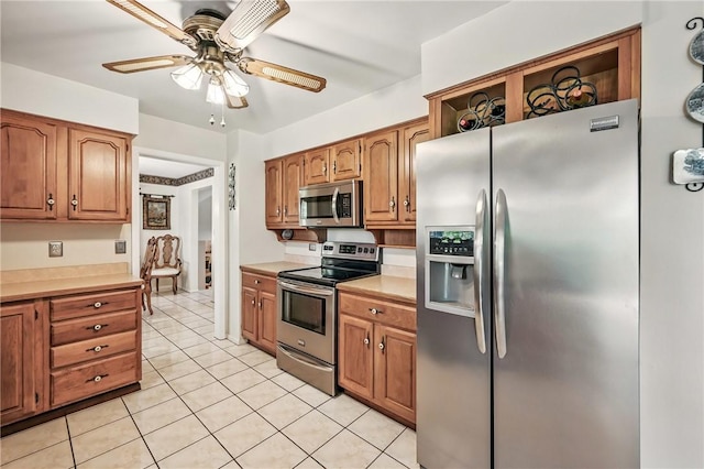 3640 Ridgewood Dr, Hermitage, PA 16148 - kitchen with light tile patterned flooring, ceiling fan, appliances with stainless steel finishes, light countertops, and brown cabinetry
