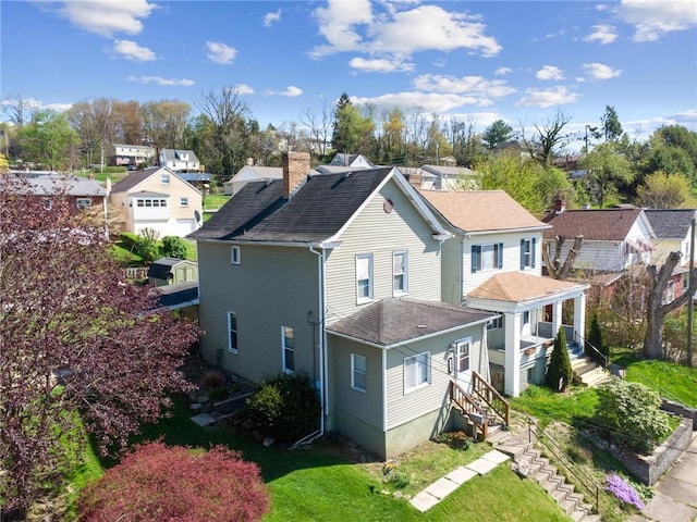 rear view of property with a residential view, a chimney, and roof with shingles