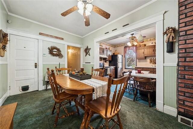 dining space featuring dark colored carpet, ornamental molding, baseboards, and ceiling fan