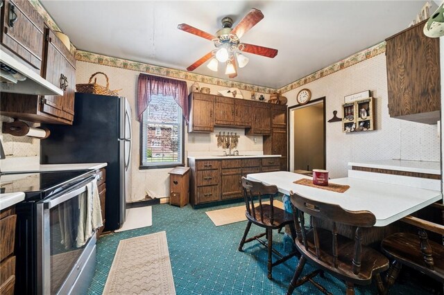 kitchen with stainless steel electric stove, light countertops, ceiling fan, and wallpapered walls