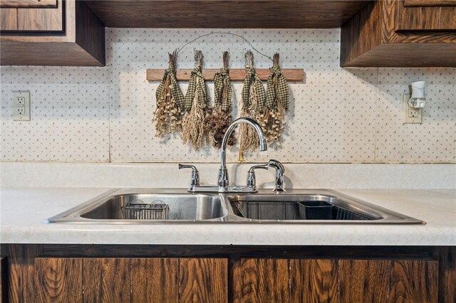kitchen featuring a sink, light countertops, decorative backsplash, and dark brown cabinetry