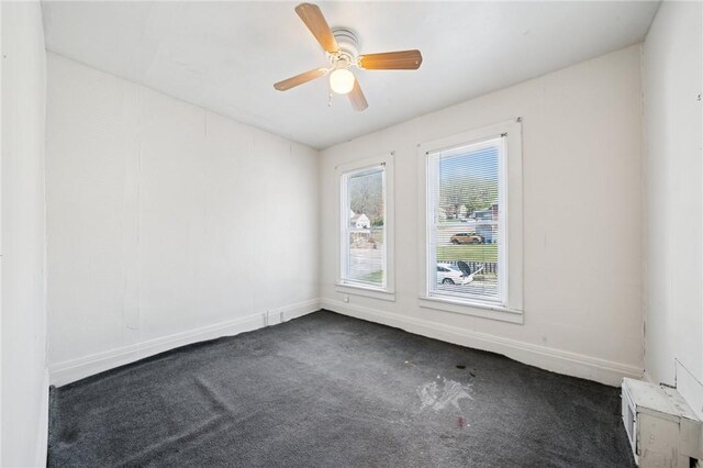 unfurnished room featuring baseboards, ceiling fan, and dark carpet