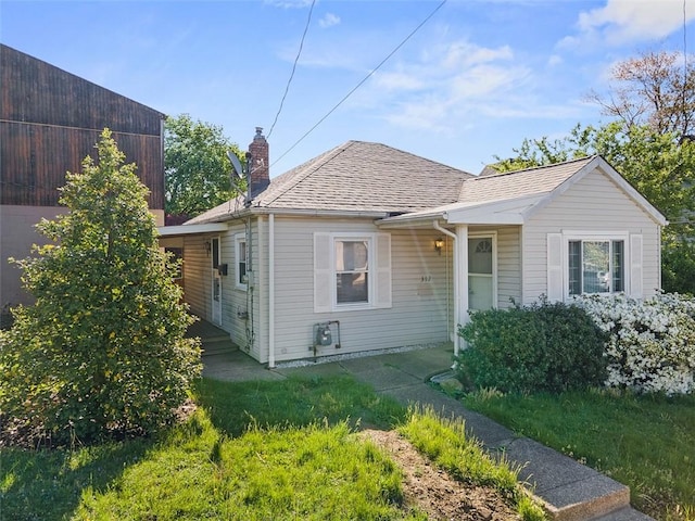bungalow featuring roof with shingles and a chimney