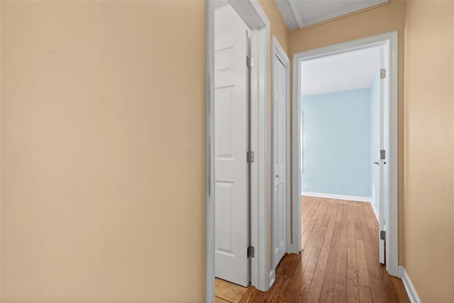 hall featuring baseboards, attic access, and hardwood / wood-style flooring