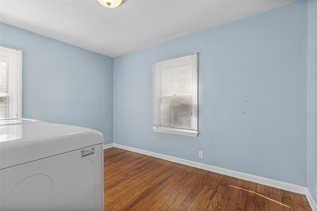 clothes washing area with washer / dryer, baseboards, and wood finished floors