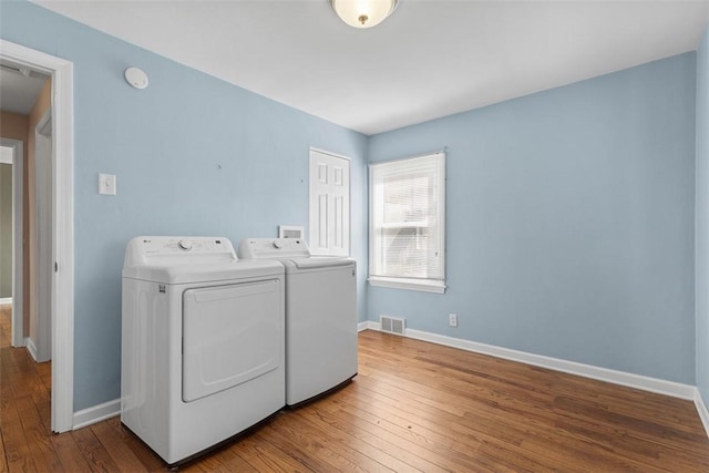 clothes washing area with wood-type flooring, laundry area, baseboards, and washer and clothes dryer