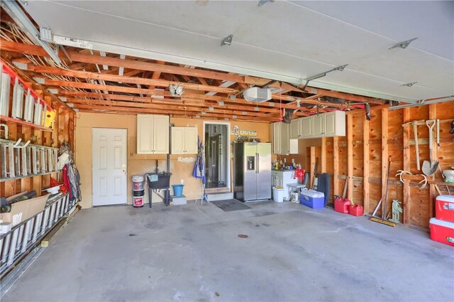 garage with stainless steel fridge and a garage door opener