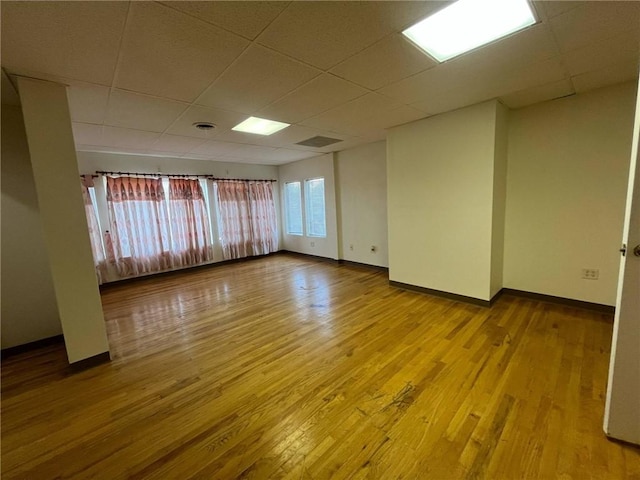 empty room with wood finished floors, baseboards, and a drop ceiling