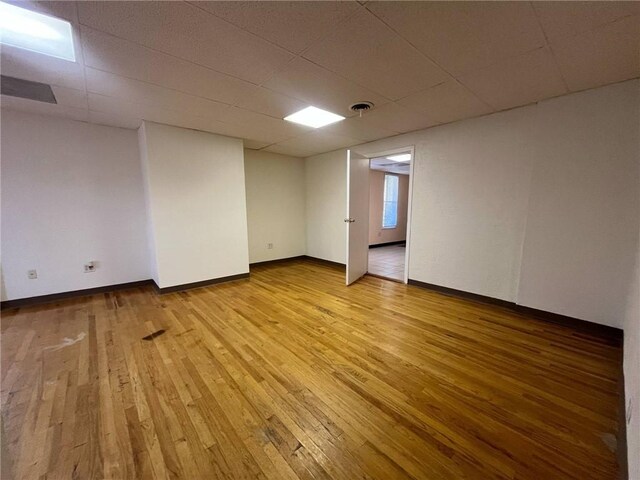 finished below grade area featuring baseboards, light wood-style flooring, and a paneled ceiling