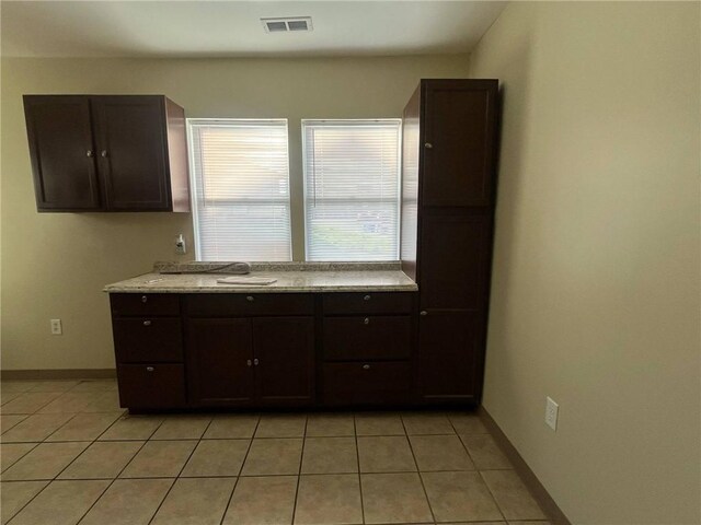 kitchen featuring light tile patterned floors, light countertops, dark brown cabinetry, and visible vents