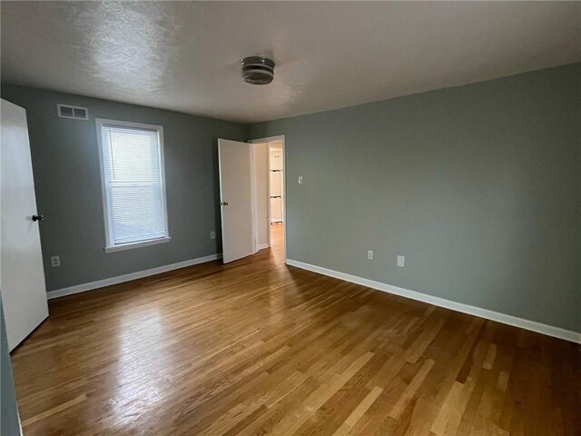 unfurnished room featuring visible vents, baseboards, and wood finished floors