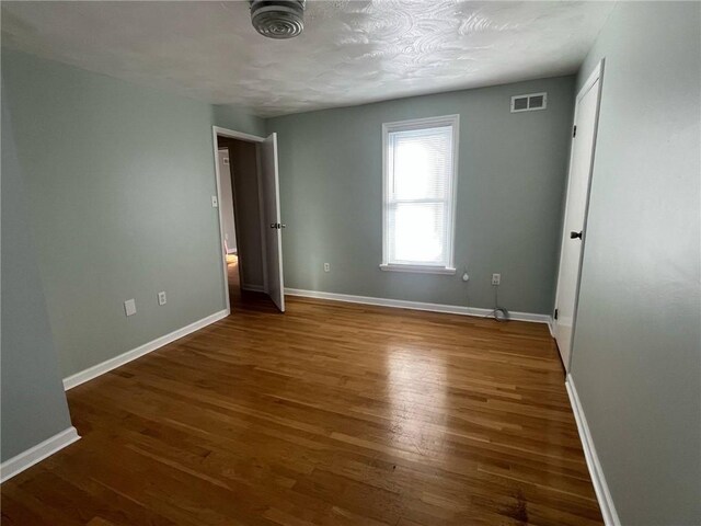 unfurnished bedroom with visible vents, baseboards, and wood finished floors