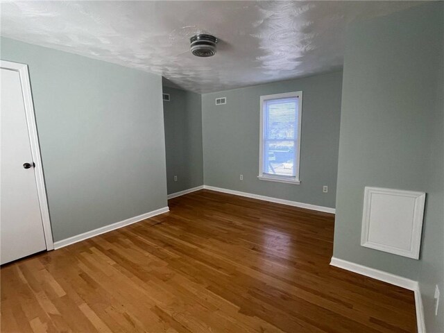 empty room with baseboards, wood finished floors, and visible vents