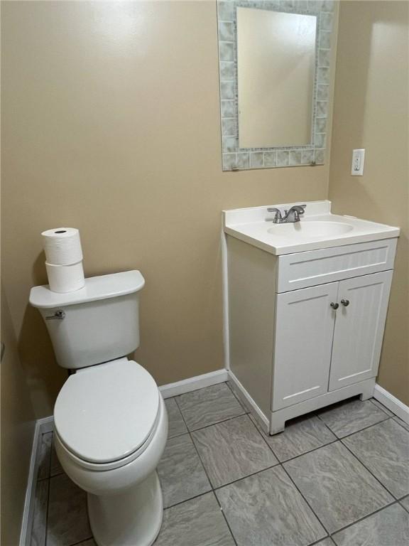 bathroom featuring baseboards, vanity, and toilet