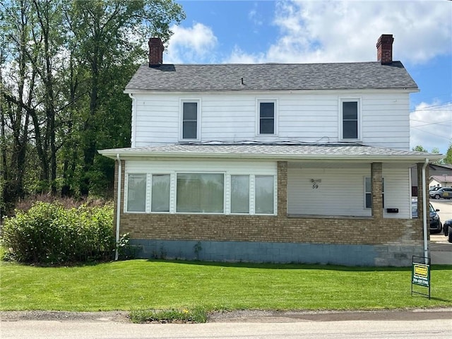 view of front of property featuring a chimney, a front lawn, and brick siding