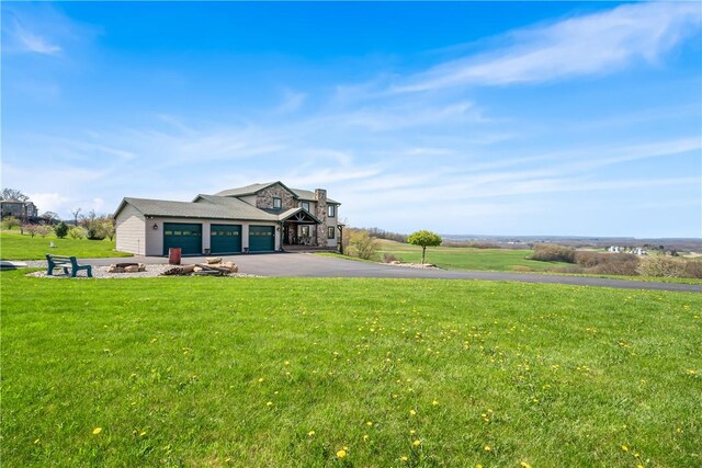 view of front facade featuring an attached garage, aphalt driveway, a fire pit, and a front yard