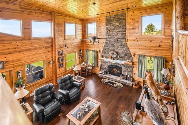 living room with a stone fireplace, wood walls, and wood ceiling