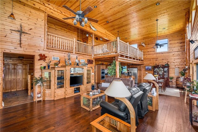 living room with wooden walls, ceiling fan, and a towering ceiling