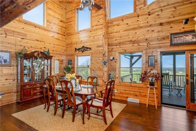 dining area featuring plenty of natural light, wood walls, and a towering ceiling