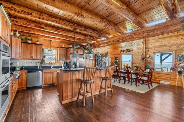 kitchen featuring dark wood-style flooring, dark countertops, a center island, brown cabinets, and stainless steel appliances