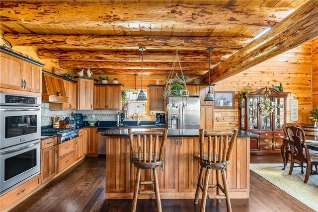 kitchen featuring dark countertops, beamed ceiling, dark wood-type flooring, wood ceiling, and appliances with stainless steel finishes