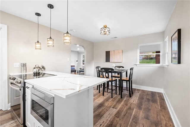 kitchen with baseboards, electric stove, dark wood-style flooring, and arched walkways