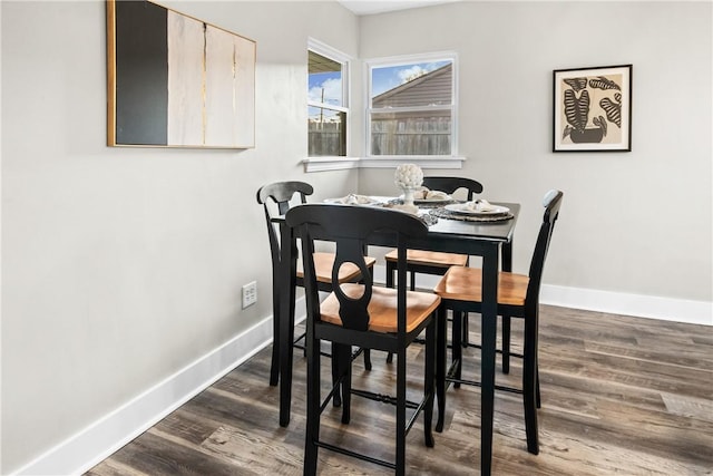 dining space with baseboards and dark wood-type flooring