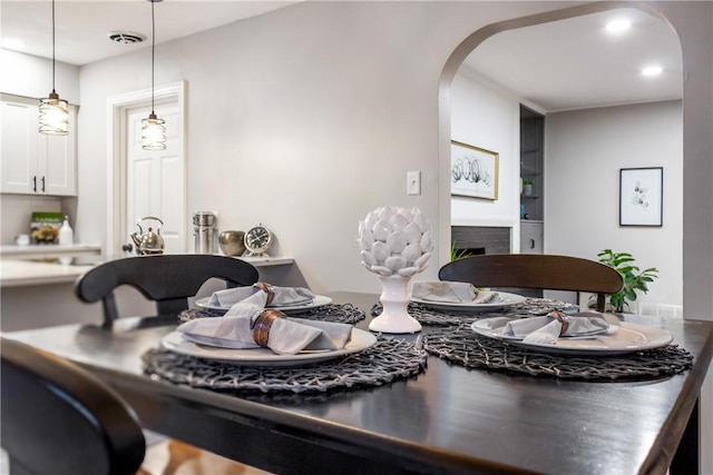dining room featuring visible vents, arched walkways, a fireplace, built in shelves, and recessed lighting