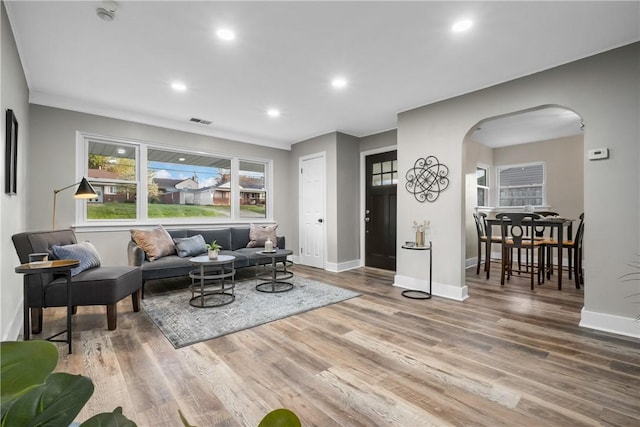 living area with arched walkways, baseboards, and wood finished floors
