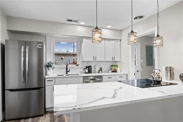 kitchen with visible vents, a sink, light stone counters, and stainless steel appliances