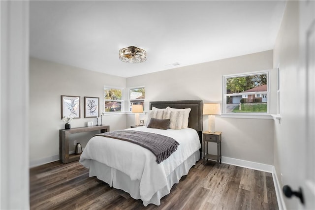 bedroom with baseboards, wood finished floors, and multiple windows