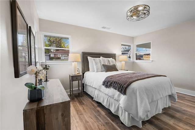 bedroom featuring baseboards, multiple windows, dark wood-type flooring, and visible vents