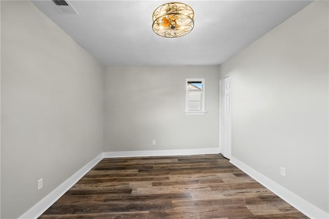 unfurnished room with an inviting chandelier, baseboards, wood finished floors, and visible vents