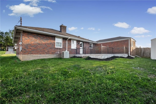 back of property featuring a lawn, brick siding, fence, and a chimney
