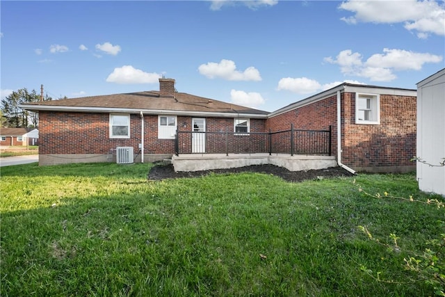rear view of property featuring a lawn, brick siding, central AC unit, and a chimney