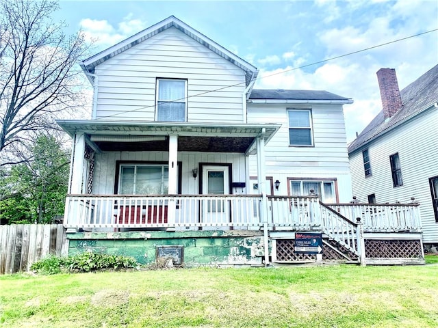 rear view of house featuring a porch, a lawn, and fence