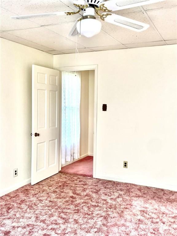 carpeted empty room featuring a ceiling fan and a paneled ceiling
