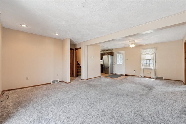 unfurnished living room featuring stairway, baseboards, light colored carpet, and visible vents