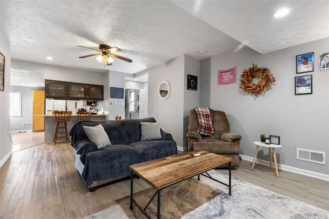 living room featuring ceiling fan, light wood finished floors, recessed lighting, baseboards, and visible vents