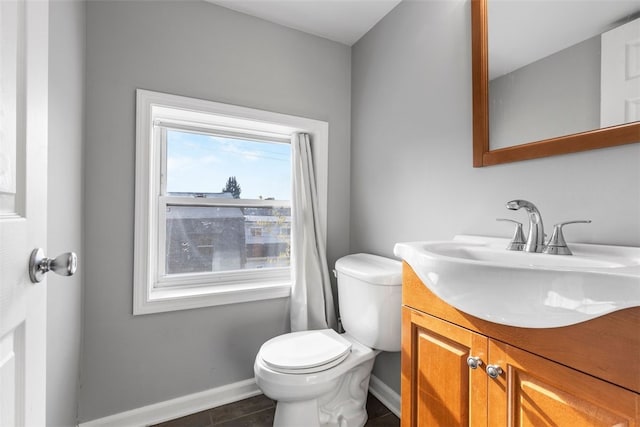 bathroom with baseboards, tile patterned flooring, toilet, and vanity